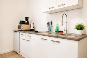 Eine moderne Küche mit weißen Schränken, einer Edelstahl-Spüle und einer Kaffeemaschine.