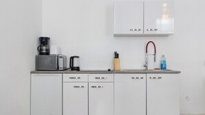 Ett litet, praktiskt kök med mikrovågsugn, kaffebryggare och en diskho med en röd kran.