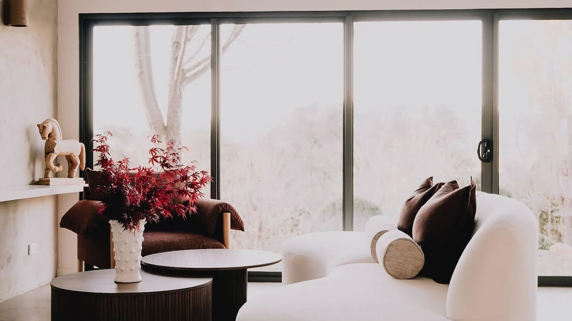 A modern living room with a sofa, armchair, and a small table with a vase.