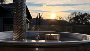 Boblebad med metalstang og gryde på balkon med solnedgang.