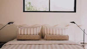 Ein Bett mit einer gestreiften Bettdecke, zwei Kissen und zwei Nachttischlampen.