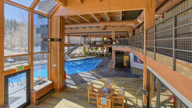 Un vaste espace intérieur doté d’une grande piscine, d’une architecture en bois et d’une mezzanine.