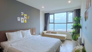 Een moderne hotelkamer met een groot bed, een bank, een raam met uitzicht op zee en wanddecoratie.