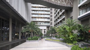 Een modern gebouw met een centrale binnenplaats, met palmbomen en plantenbakken.