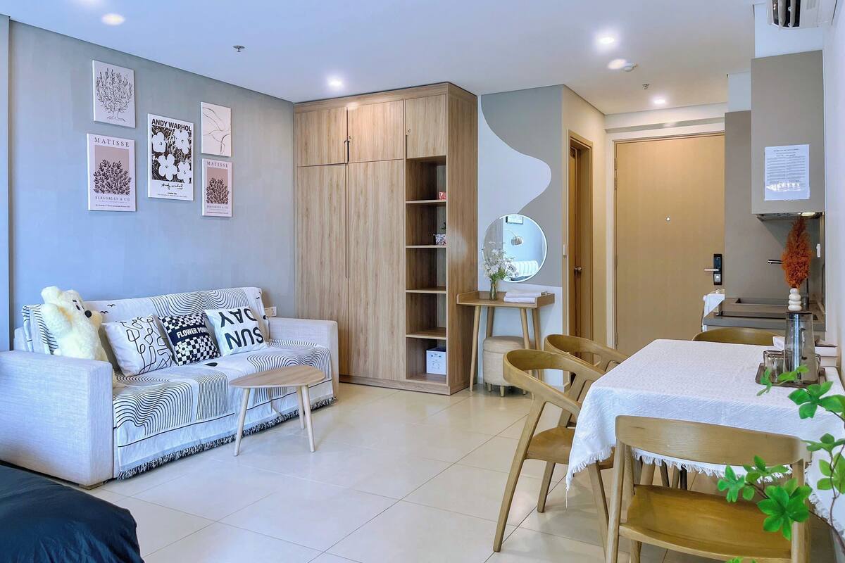Un salon moderne comprenant un canapé, une table à manger avec des chaises, une armoire en bois et des œuvres d’art murales.