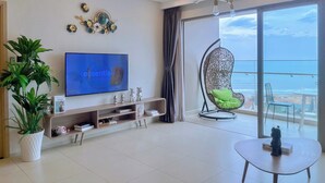 Een moderne woonkamer met een grote televisie, een hangstoel, een potplant en een balkon met uitzicht.