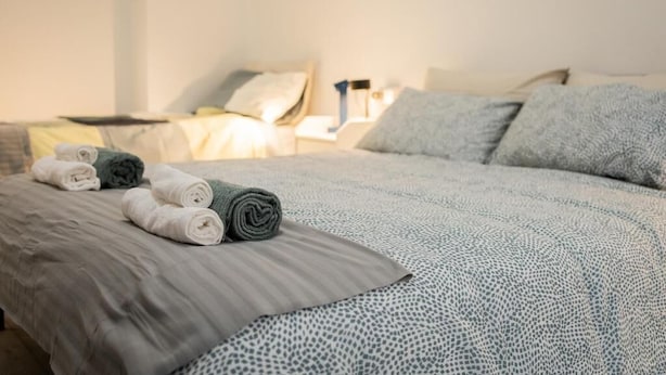 Un letto ben rifatto con asciugamani arrotolati e una coperta a motivi.