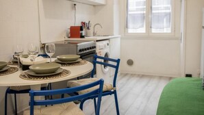 Una cucina compatta con un tavolo da pranzo per quattro persone, una lavatrice e una finestra con vista.