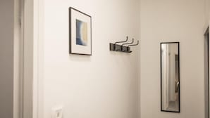 Un corridoio con un quadro astratto incorniciato, un attaccapanni e uno specchio.