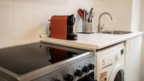 Una cucina compatta con fornello, lavatrice e lavandino.