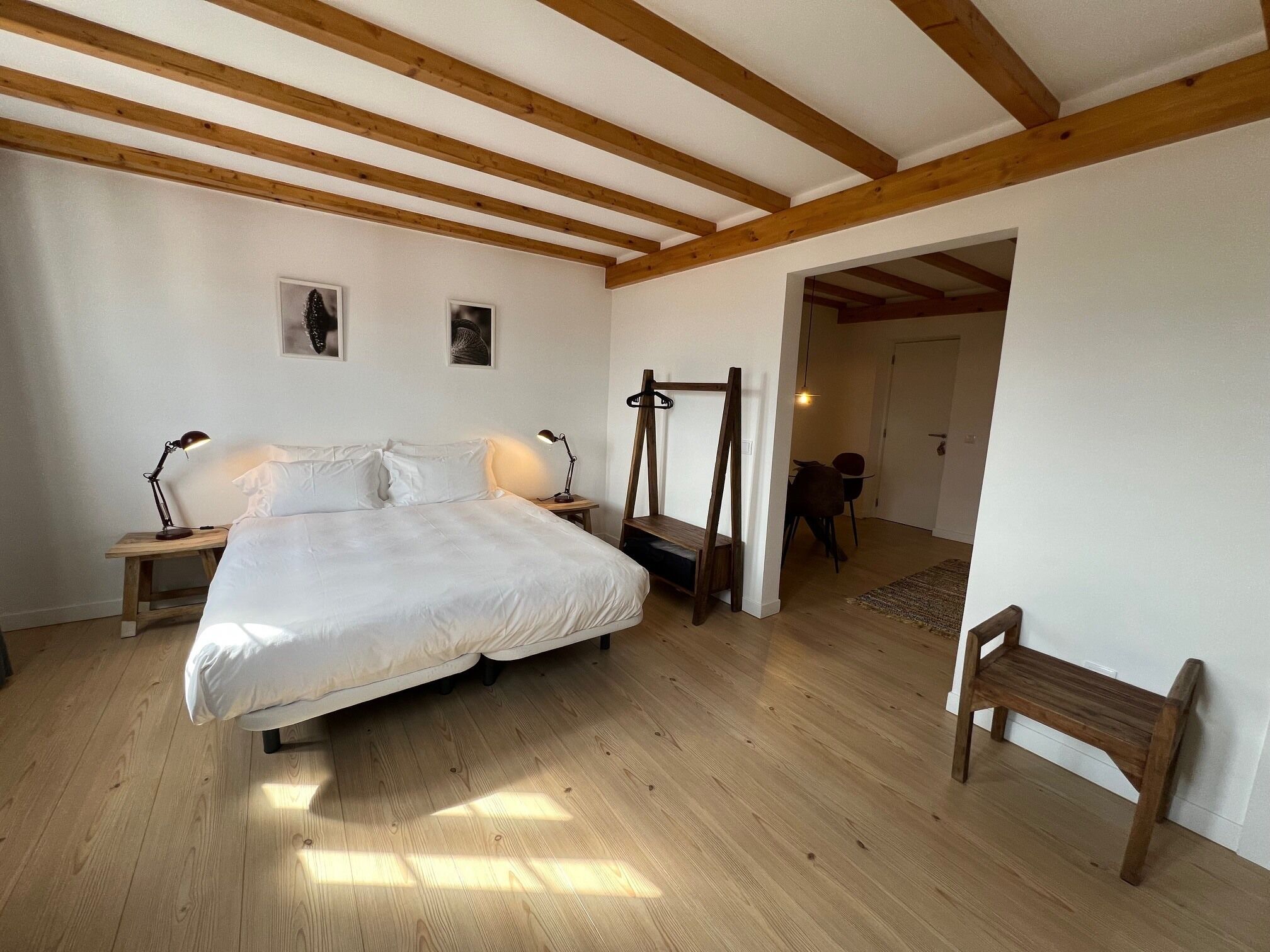 A bedroom with a wooden bed, bedside tables, a bench, and a hanging chair.