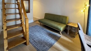 A wooden staircase leading to a loft area with a green sofa and a small table. - Constância Guest House (Constância)