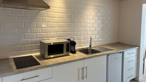 A modern kitchen with white subway tiles, stainless steel appliances, and wooden beams. - Constância Guest House (Constância)