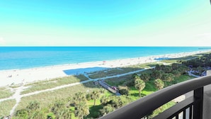 A beach view from a balcony with a clear sky, a sandy beach, and a pathway leading to a building. - Villa Zafiro by Casanita - Oceanfront Suite (Myrtle Beach)