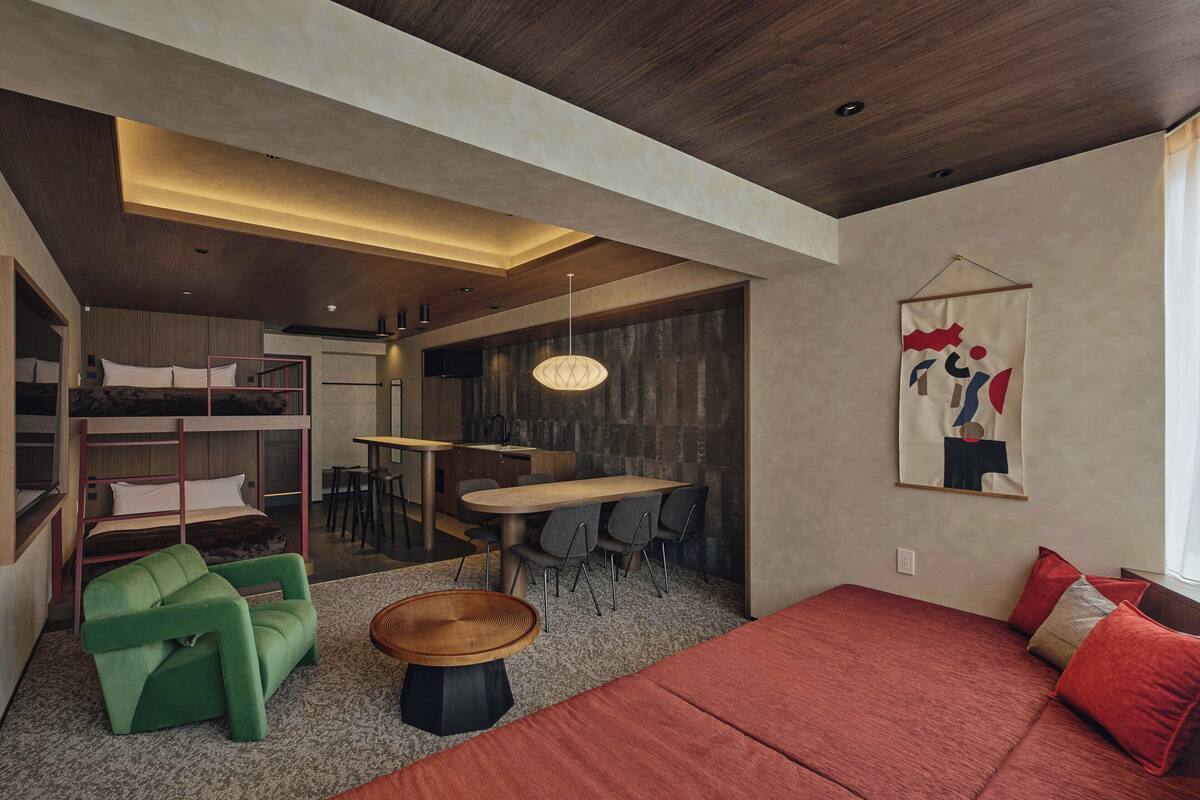A compact room with bunk beds, a dining area, and a sofa.