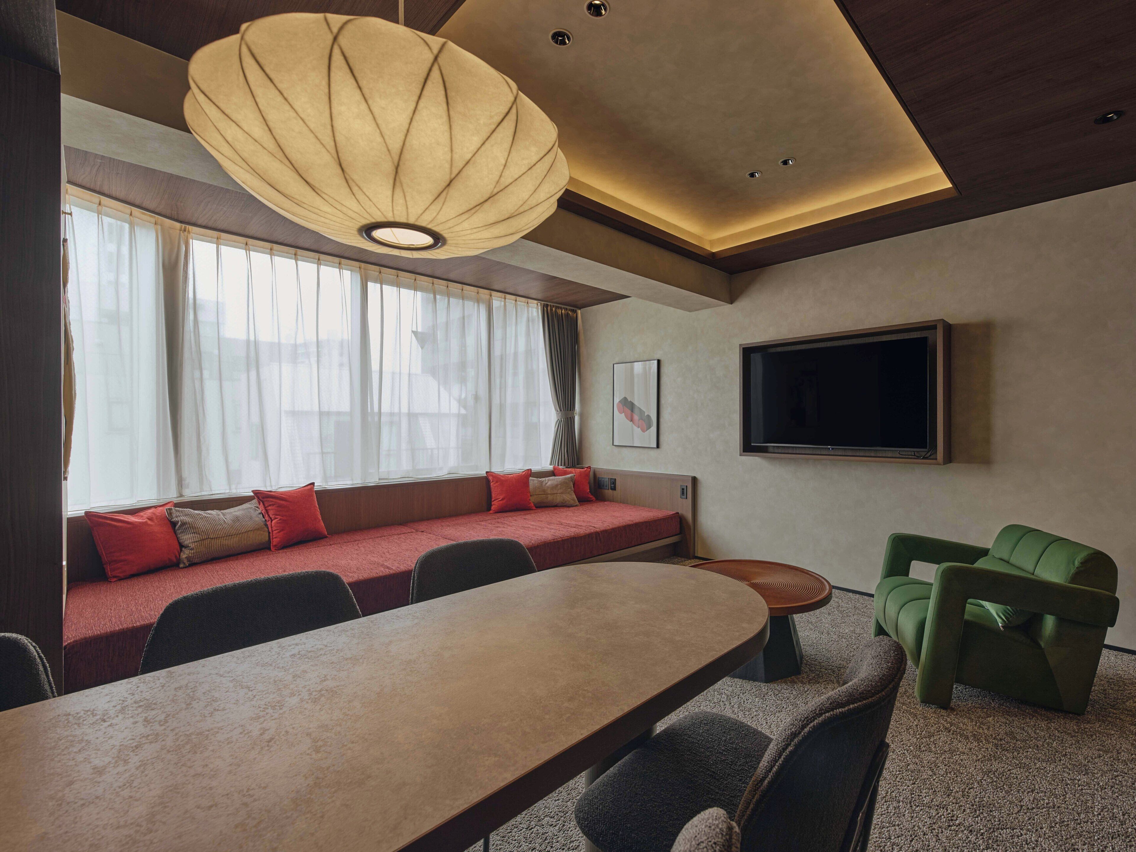 Une chambre d’hôtel moderne dotée d’une grande fenêtre, d’un canapé, d’une table à manger et d’un téléviseur à  écran plat.