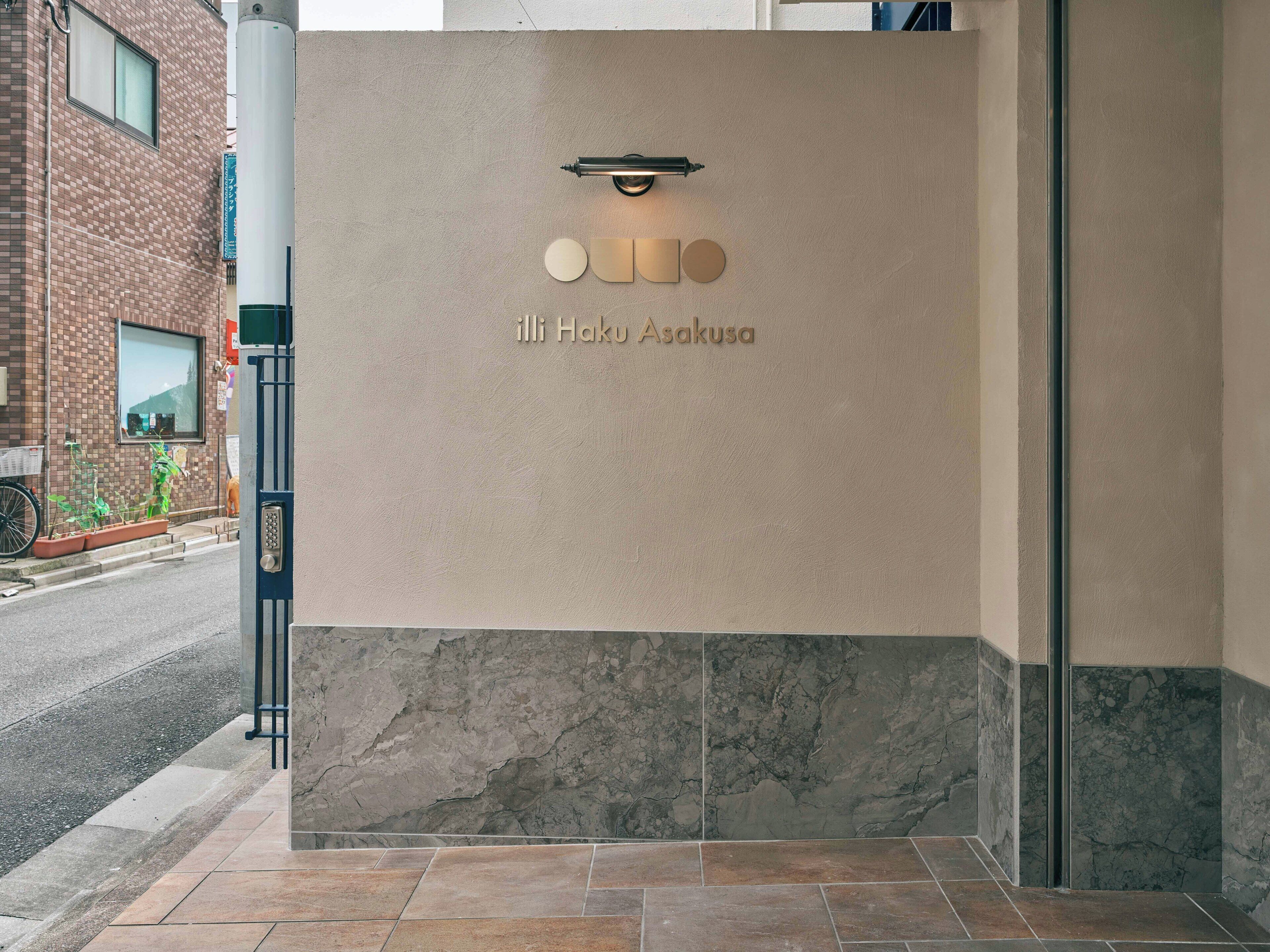A building entrance with a sign reading 'i-li Haku Asakusa' and a modern light fixture above it.
