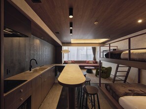 Een compacte, moderne kamer met kitchenette, een stapelbed, een eethoek en een zithoek.