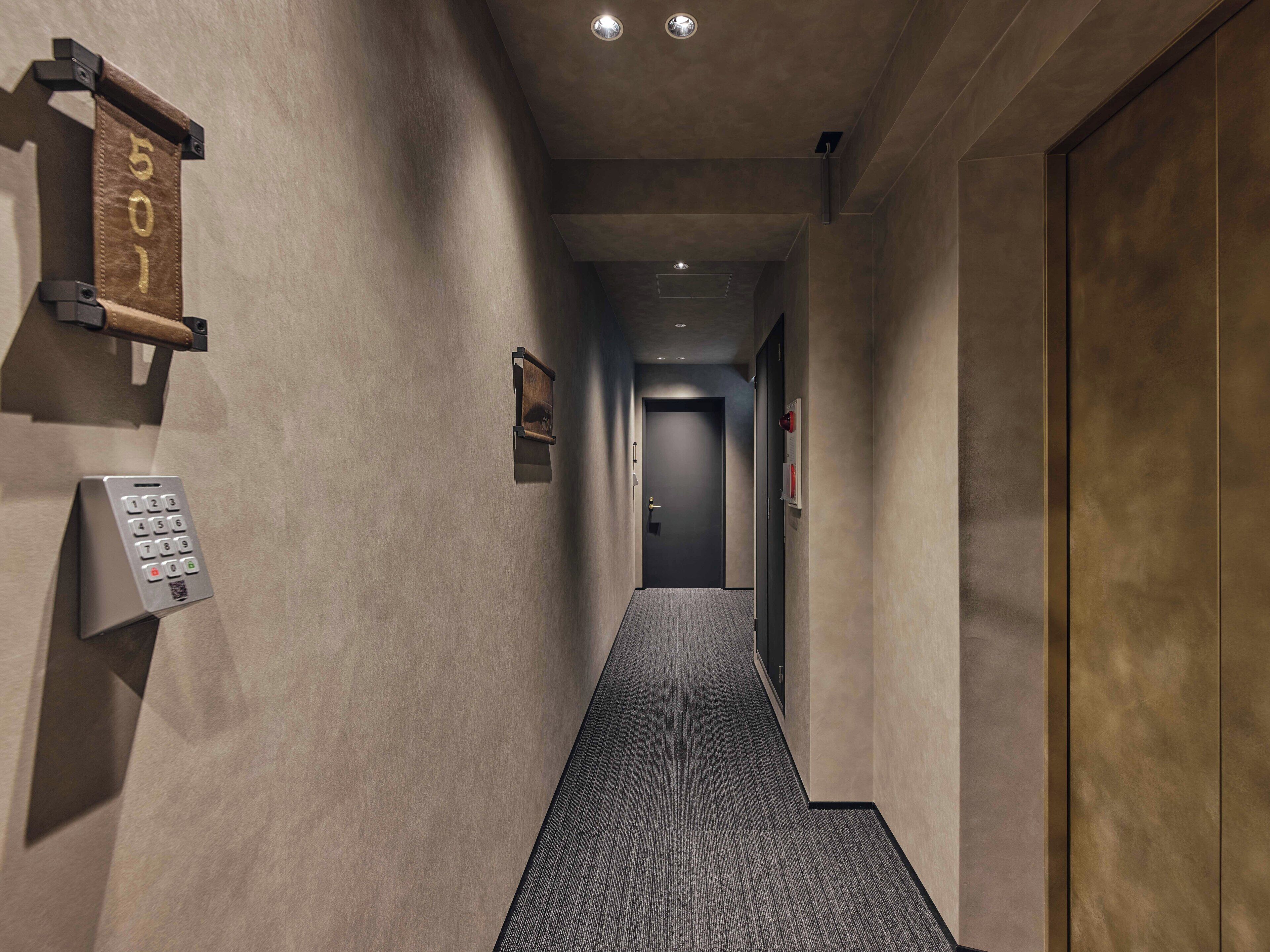 A hallway with a wall-mounted phone, a door, and a fire alarm.