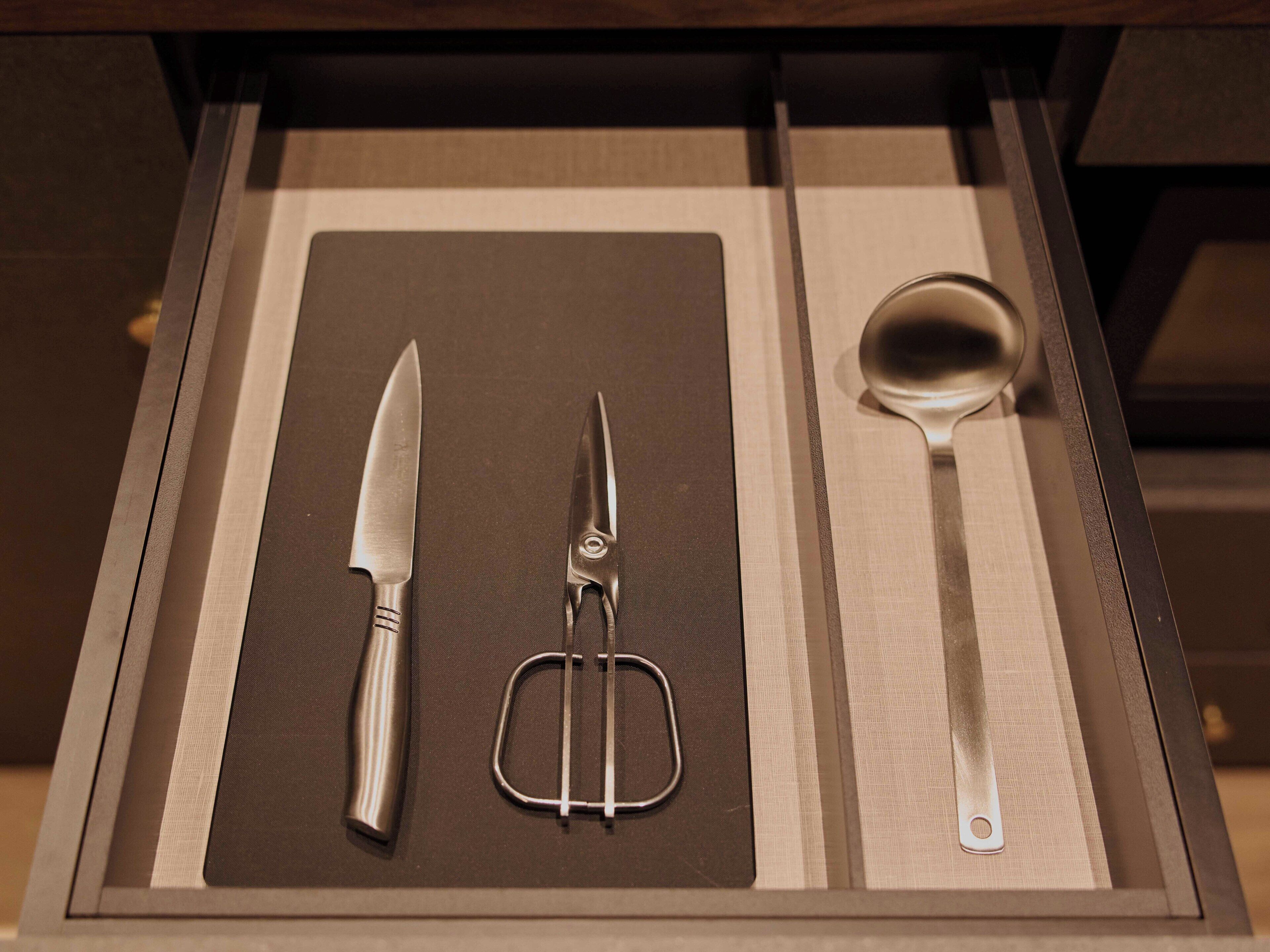 A drawer with a knife, a whisk, and a spoon.