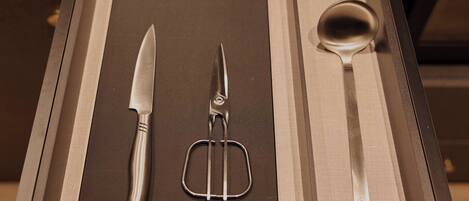 A drawer with a knife, a whisk, and a spoon.