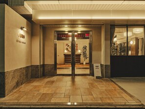 A hotel entrance with a reception desk, a potted plant, and a sign indicating the hotel's name. - illi Haku Asakusa (Tokyo)