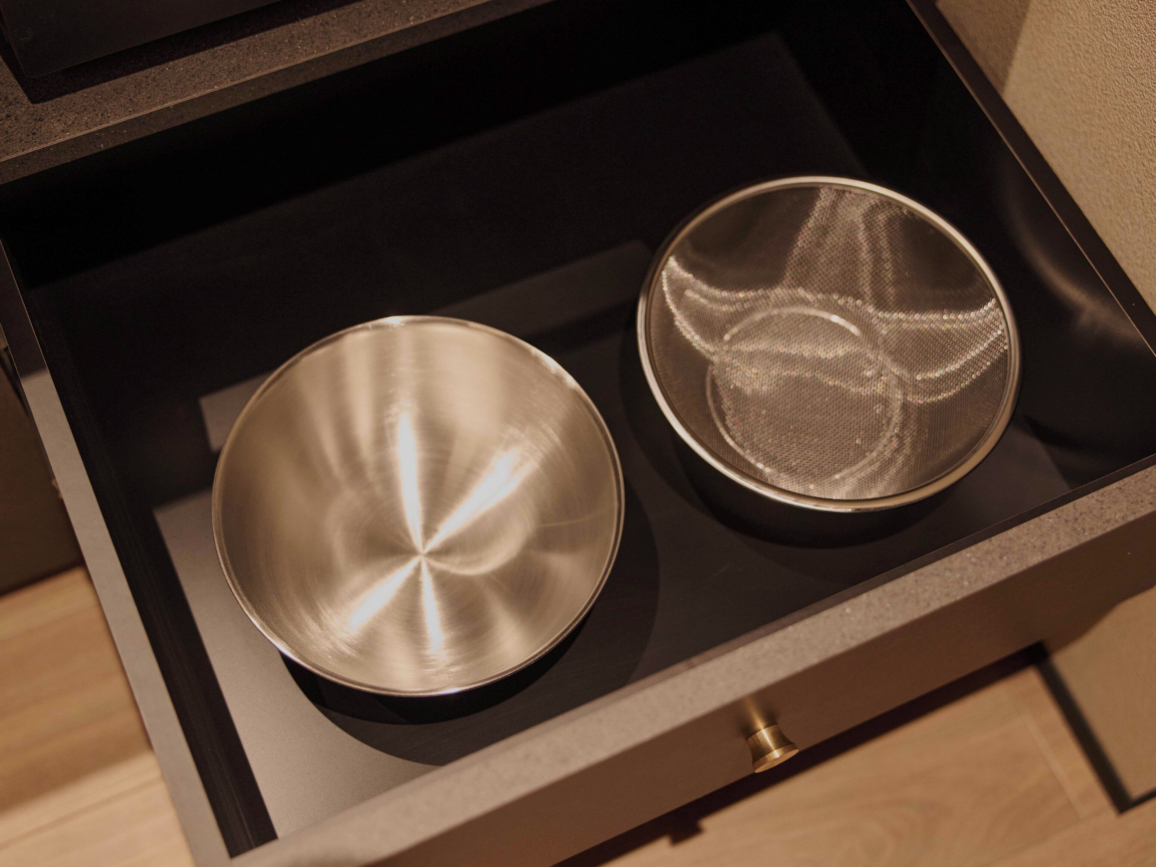 A drawer with two metallic bowls, one with a smooth surface and the other with a textured surface.