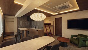 A modern kitchen with a built-in stove, a dining area with a large table and chairs, a green sofa, and a TV mounted on the wall. - illi Haku Asakusa (Tokyo)