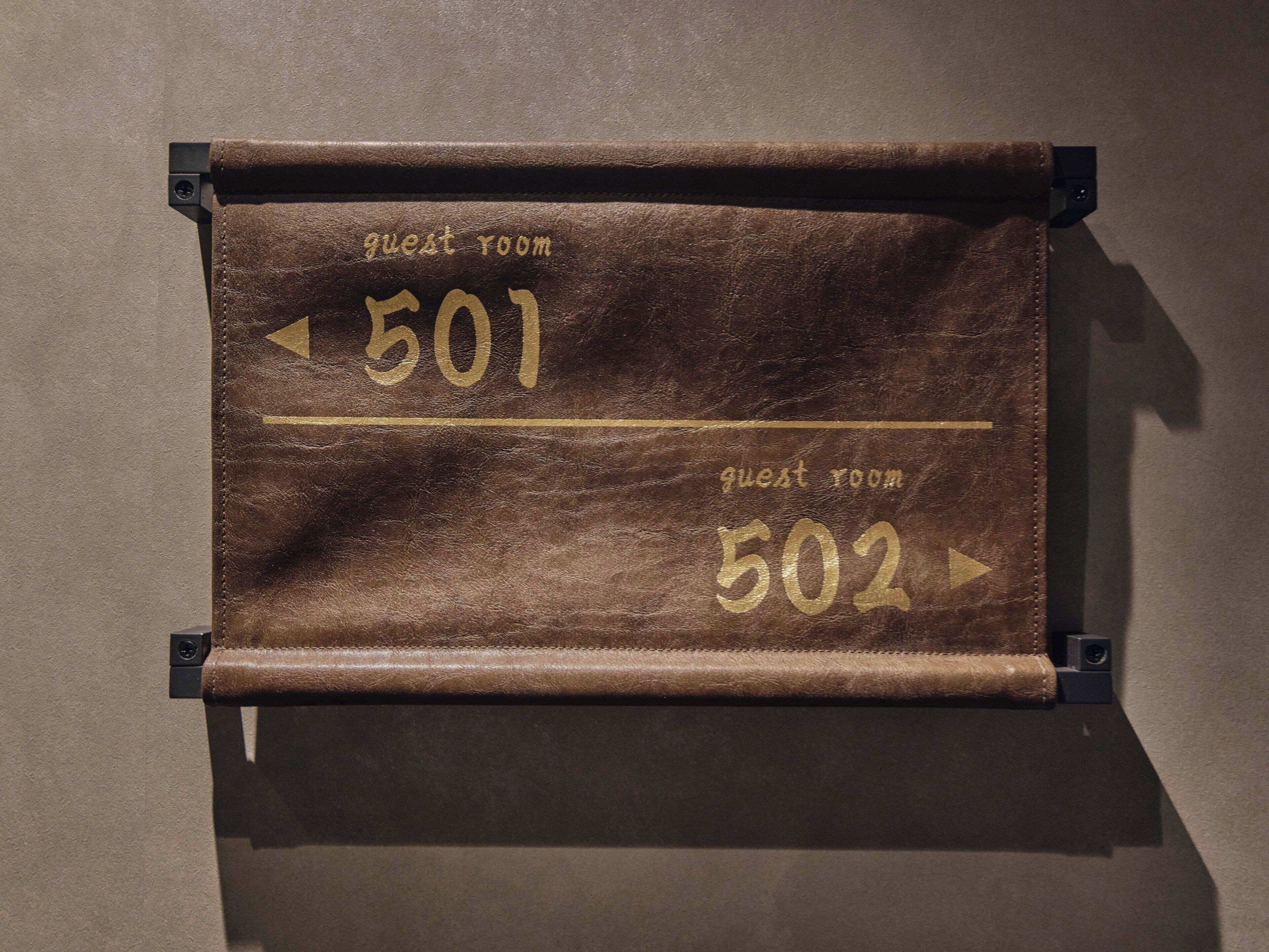 A brown leather sign with 'guest room 501' and 'guest room 502' indicating room numbers.