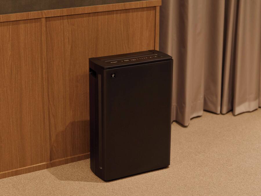 A compact black refrigerator in a room with wooden paneling and a curtain.