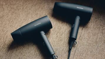 Two black hairdryers with the brand name 'SALONIA' on a textured surface.