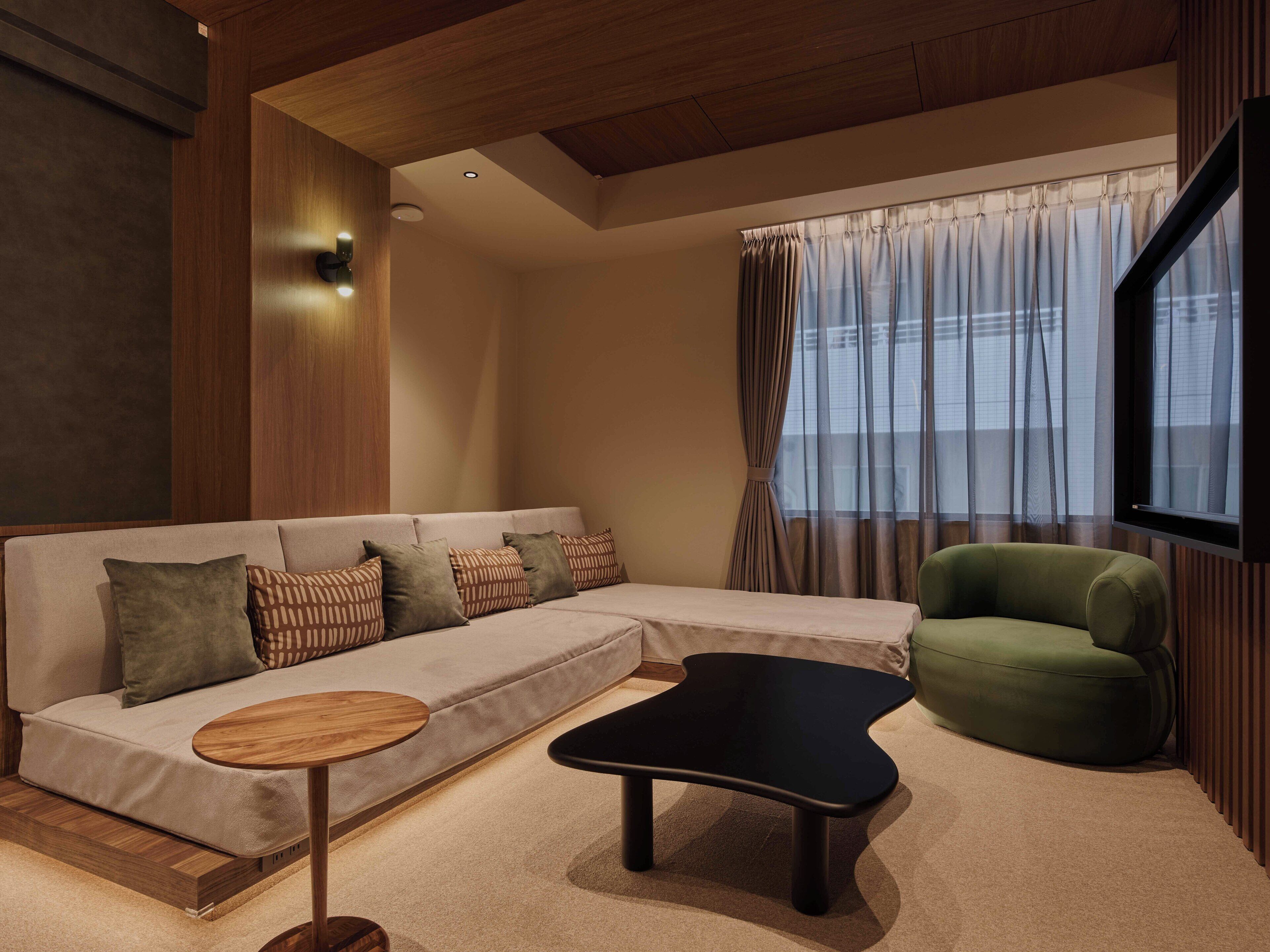 A modern living room with a sectional sofa, a round wooden coffee table, and a green armchair.