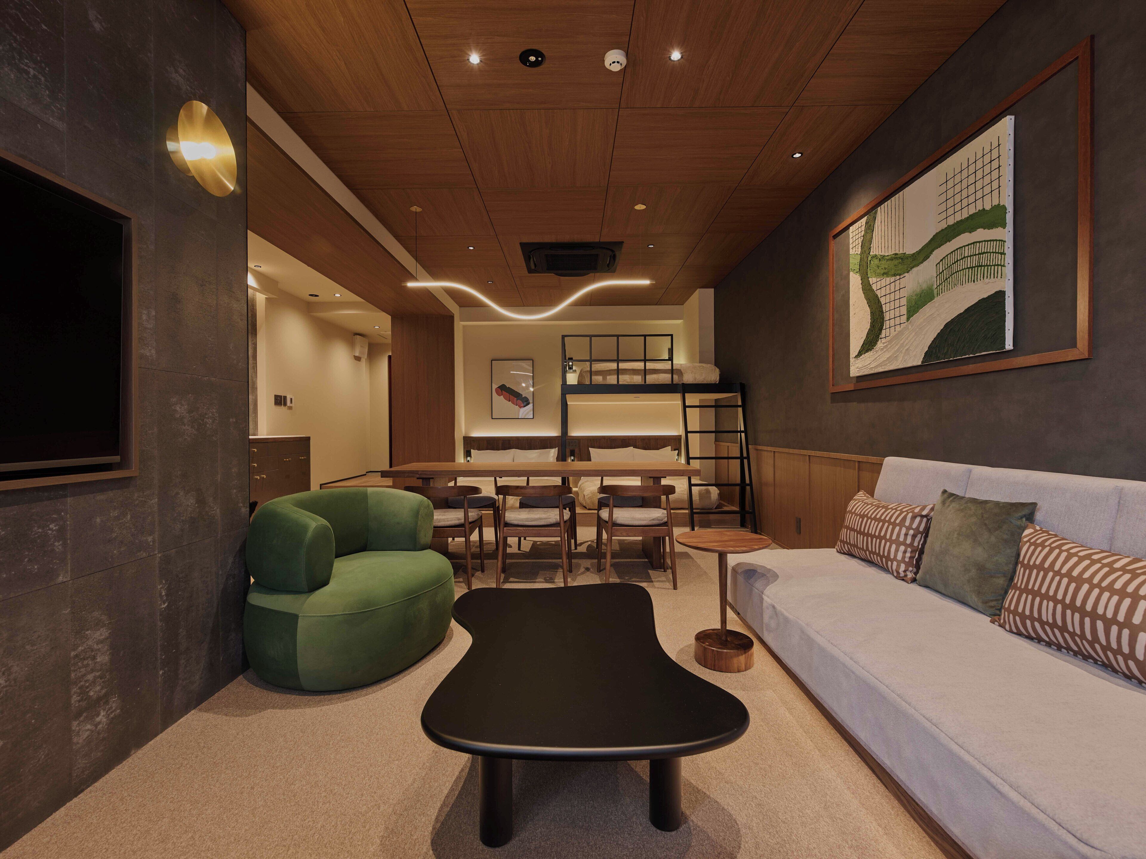 Un interior moderno con un sofá, un sillón verde, una mesita de centro negra y una cama litera.