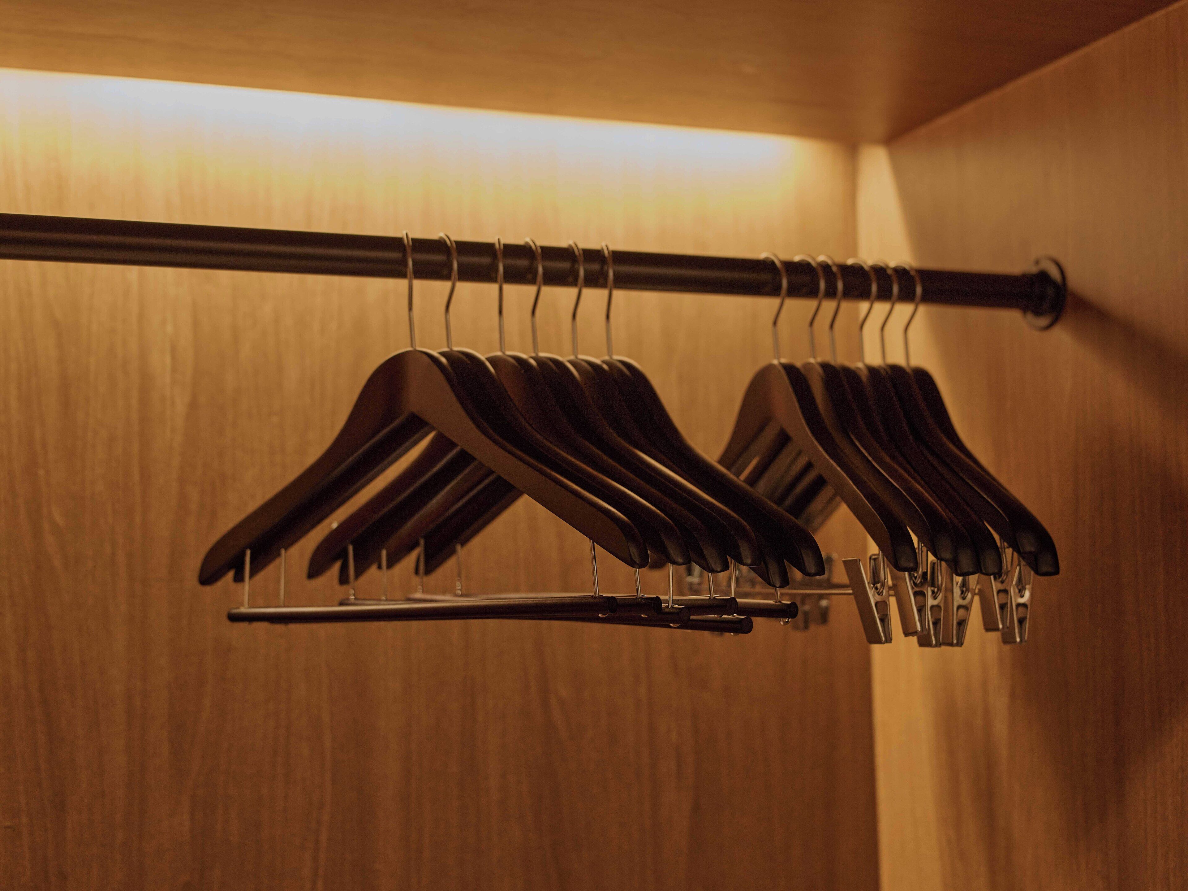 A wooden wall with a metal rod holding several black hangers.