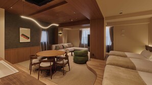 A modern hotel room with a wooden ceiling, a round dining table with chairs, a green ottoman, a sofa, and a bed. - illi Aest Shinagawa-Gotanda (Tokyo)