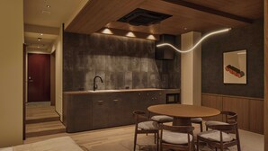 A modern kitchen with a central island, recessed lighting, and a dining area with wooden chairs and a round table. - illi Aest Shinagawa-Gotanda (Tokyo)