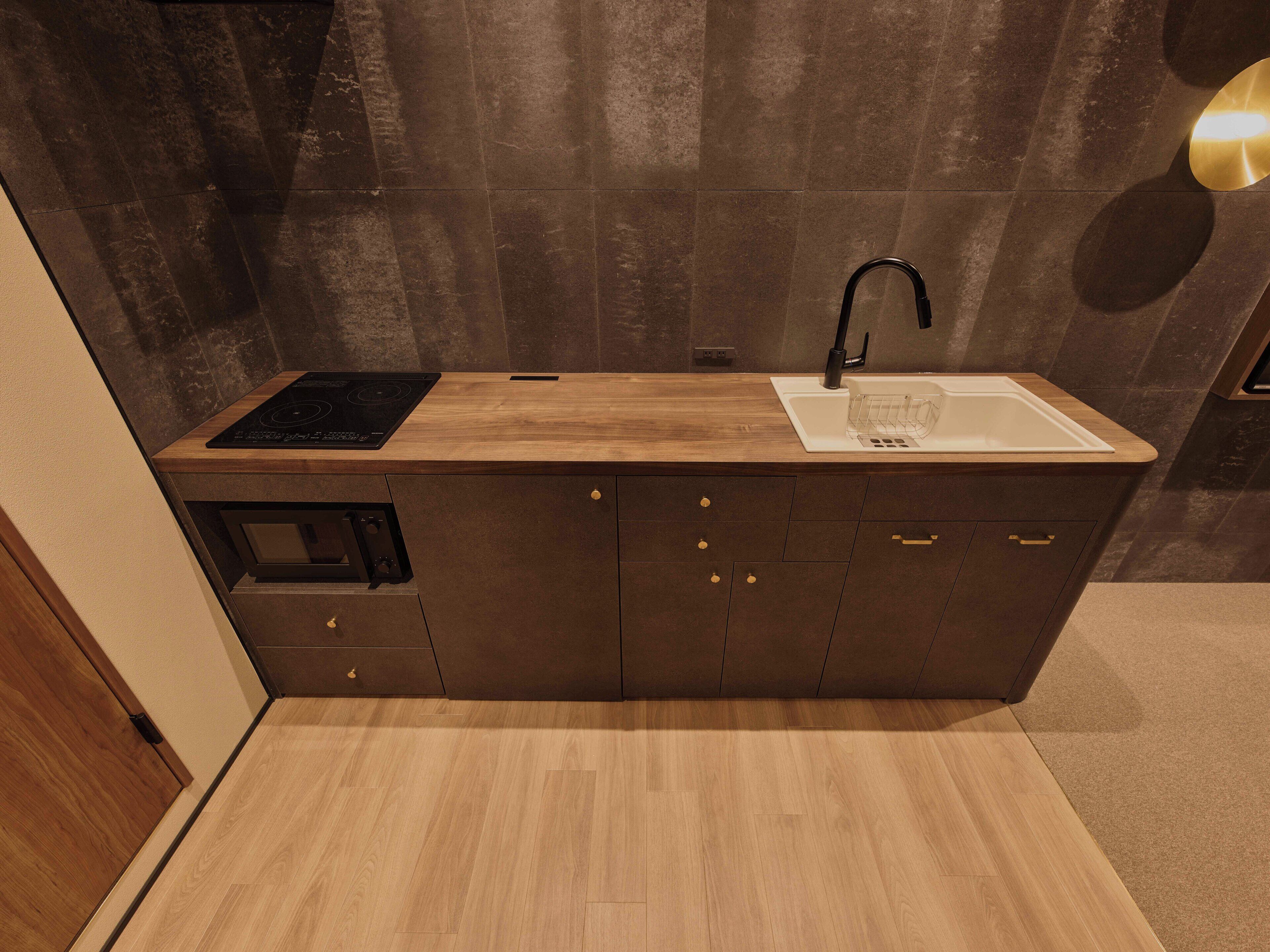 A compact kitchen with a built-in stove, a sink, and dark cabinetry.