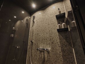 A modern bathroom with a terrazzo floor, a glass-enclosed shower, and a shelf with toiletries. - illi Aest Shinagawa-Gotanda (Tokyo)
