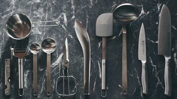 A variety of kitchen utensils laid out on a dark marble surface.