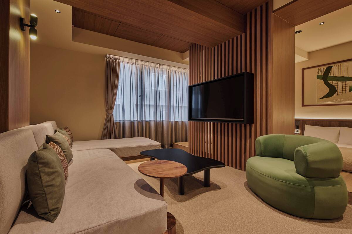 A modern living room with a sofa, a green armchair, a coffee table, and a flat-screen TV mounted on the wall.