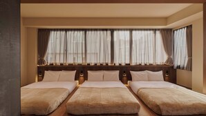 A hotel room with three beds, a large window with curtains, and a wooden headboard. - illi Aest Shinagawa-Gotanda (Tokyo)