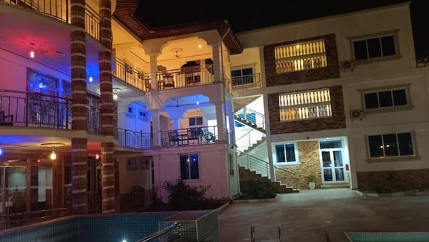 Et hotel med flere etager, altaner, swimmingpool og en godt oplyst indgang.