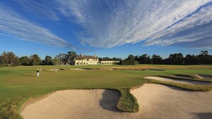 A golf course with bunkers, a clubhouse, and a clear sky. - Elegant East Melbourne Escape | Pool+Gym+Parking (East Melbourne)
