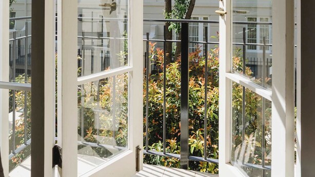 An open balcony with a view of a residential area and trees. - Elegant East Melbourne Escape | Pool+Gym+Parking (East Melbourne)