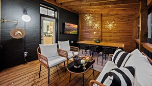 A cozy wooden interior with a dining area, wicker furniture, and a decorative light fixture. - Gatsby-inspired mansion w/ game lounge & hot tub! (Louisville)
