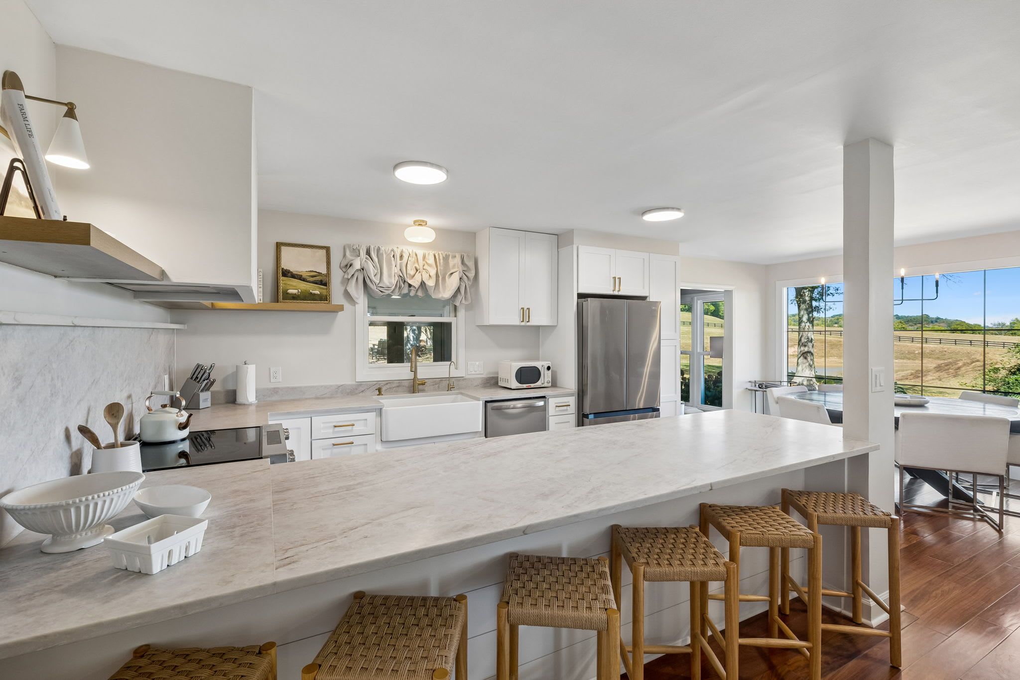 A modern kitchen with a large island, white cabinetry, and a view of the outdoors.