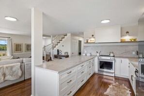 Una cocina moderna con armarios blancos, una isla central y un horno empotrado.