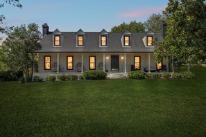 A two-story house with a covered porch, multiple windows, and a well-maintained lawn. - Luxe Franklin Home| 15 Acres w Pond & Game Room (Franklin)