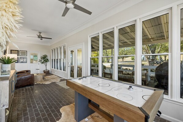 A kitchen with a large island, a ceiling fan, and a view of the outdoor patio area.