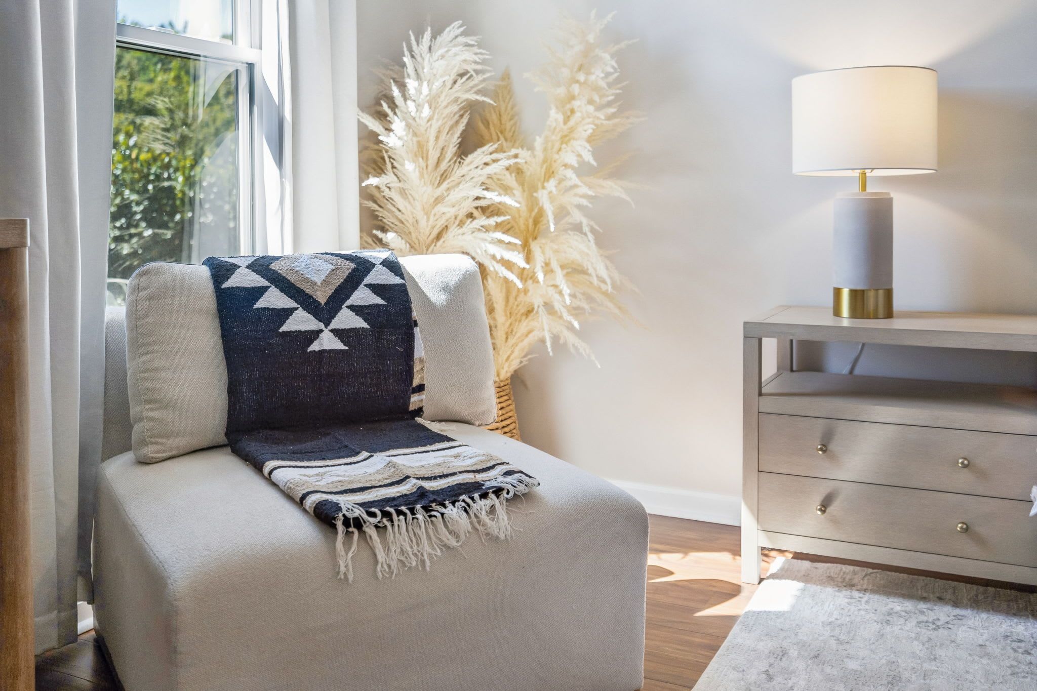 Un coin salon confortable avec un banc rembourré, un coussin décoratif et une lampe posée sur une table de chevet.